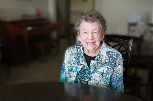 Smiling resident sitting at a table in a common area