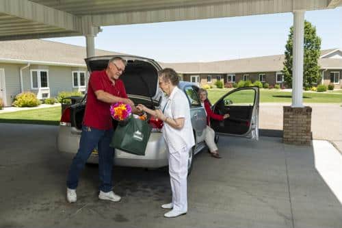 Staff assisting a resident with bags in the parking area