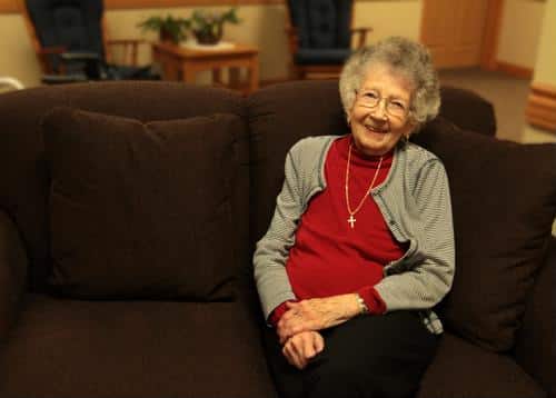 An elderly resident smiling while seated on a couch