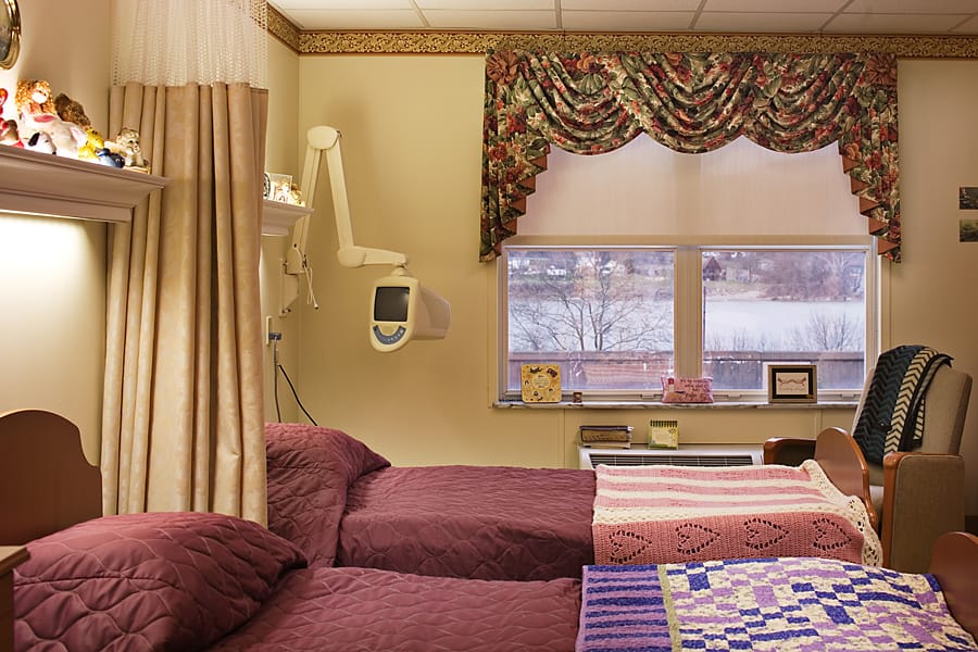 A well-decorated shared bedroom with two beds, floral curtains, and window view.
