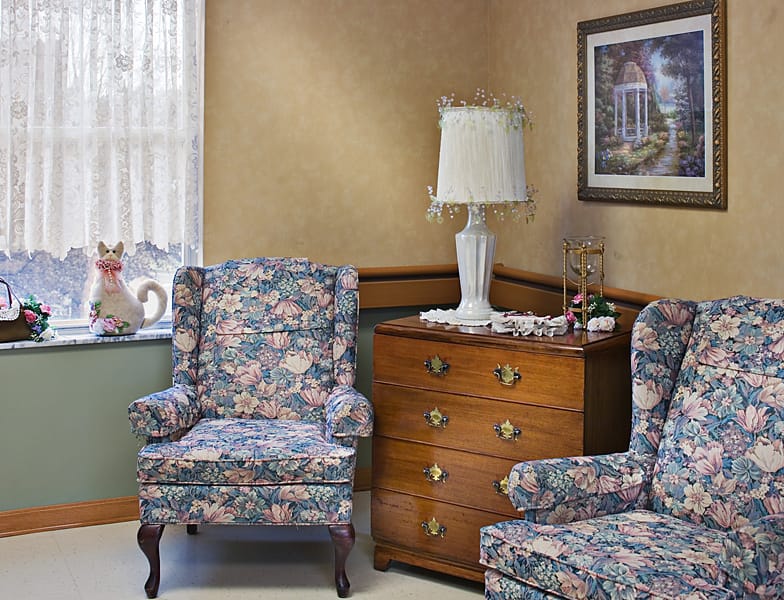 Floral-patterned chairs and a wooden dresser in a living room.