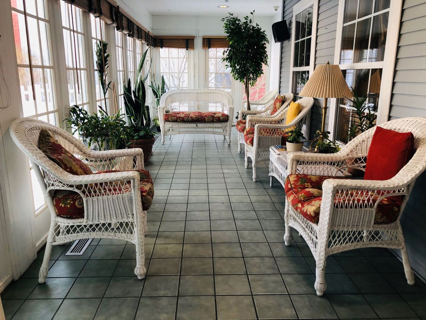 Sunroom with wicker chairs and plants at Heritage Woods.