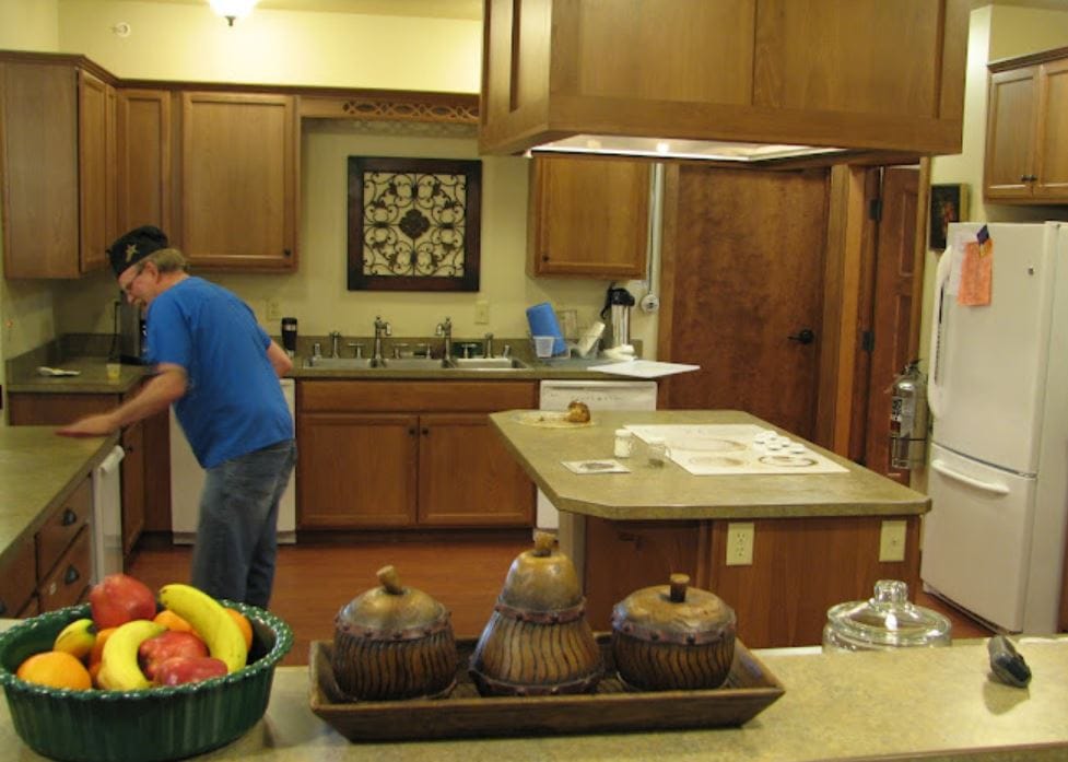 A resident cleaning the kitchen counter in a cozy kitchen setting.