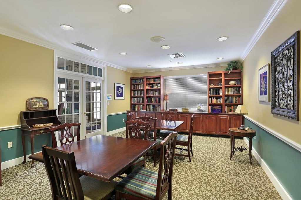 A spacious common area with a dining table, bookshelves, and comfortable seating.