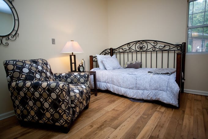 A well-furnished bedroom with a bed, armchair, and lamp.