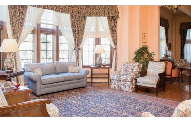 Bright living room with large windows, comfortable seating, and decorative plants