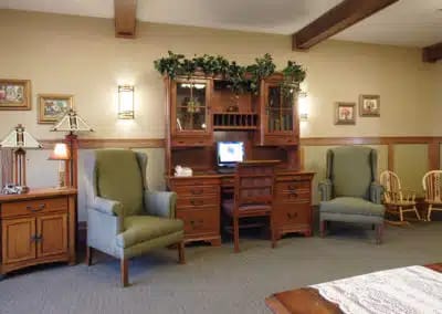 A cozy living room with two armchairs and a wooden desk in Hillcrest Country Estates.