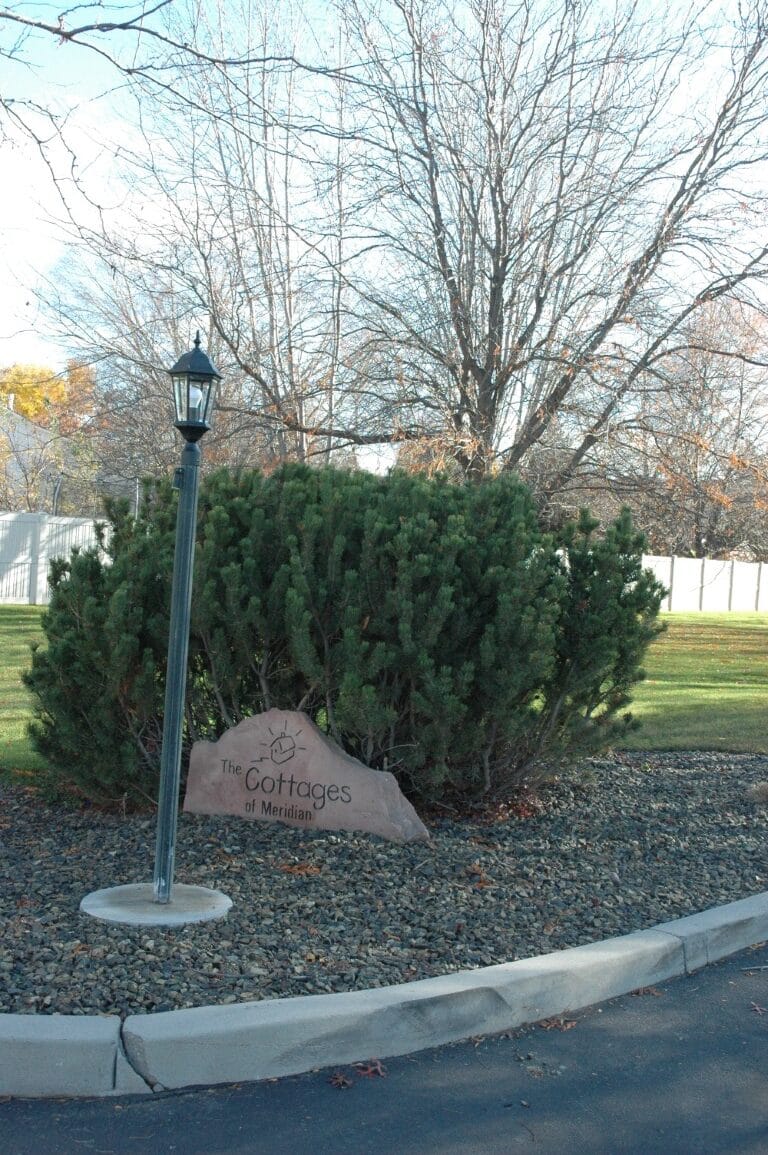 Sign for The Cottages of Meridian surrounded by greenery