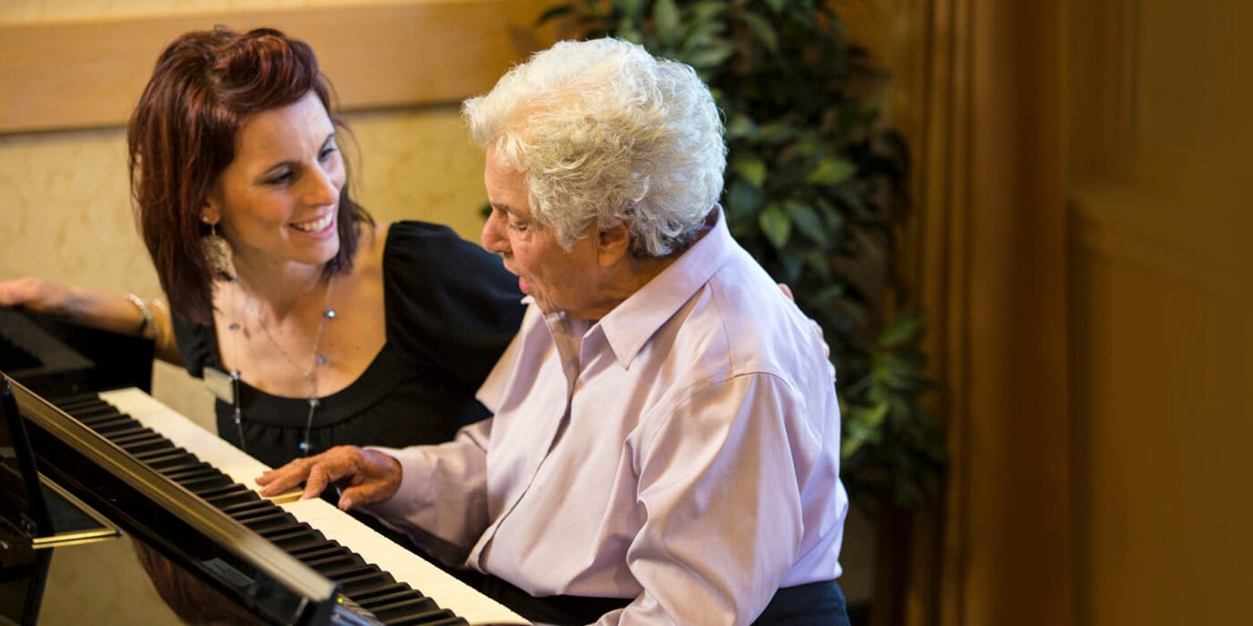 Resident and staff member playing piano together