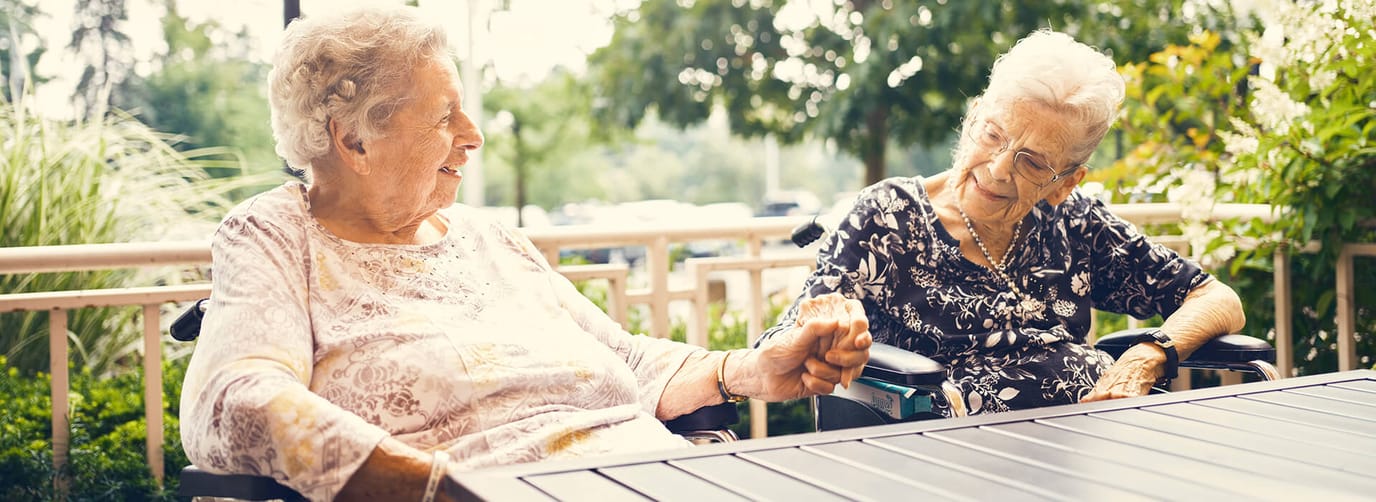 Two elderly women enjoying a conversation outdoors.