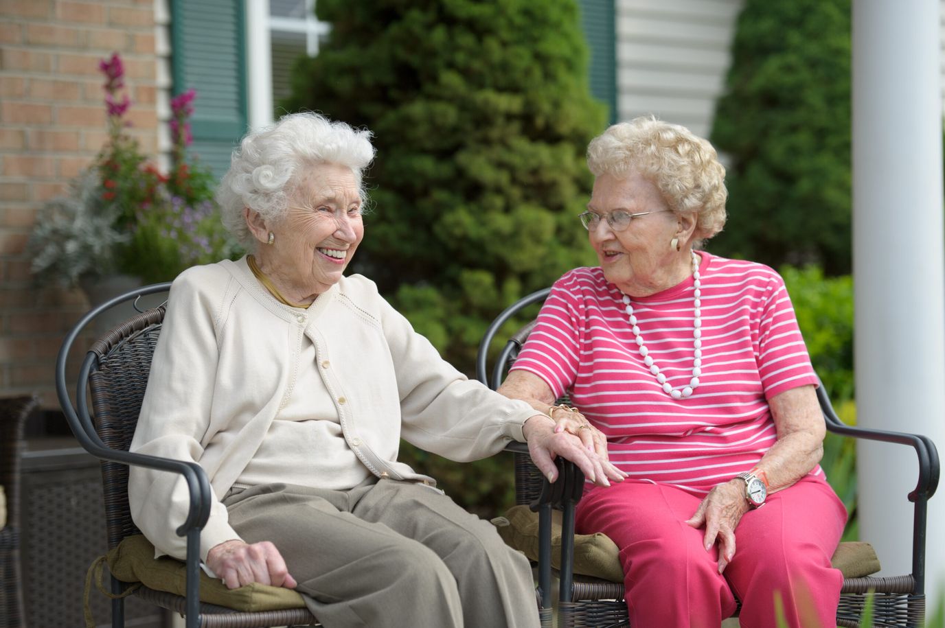 Two elderly women laughing together on a patio