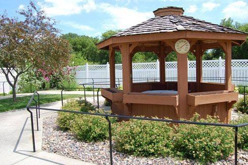 Wooden gazebo surrounded by greenery in a senior living facility.