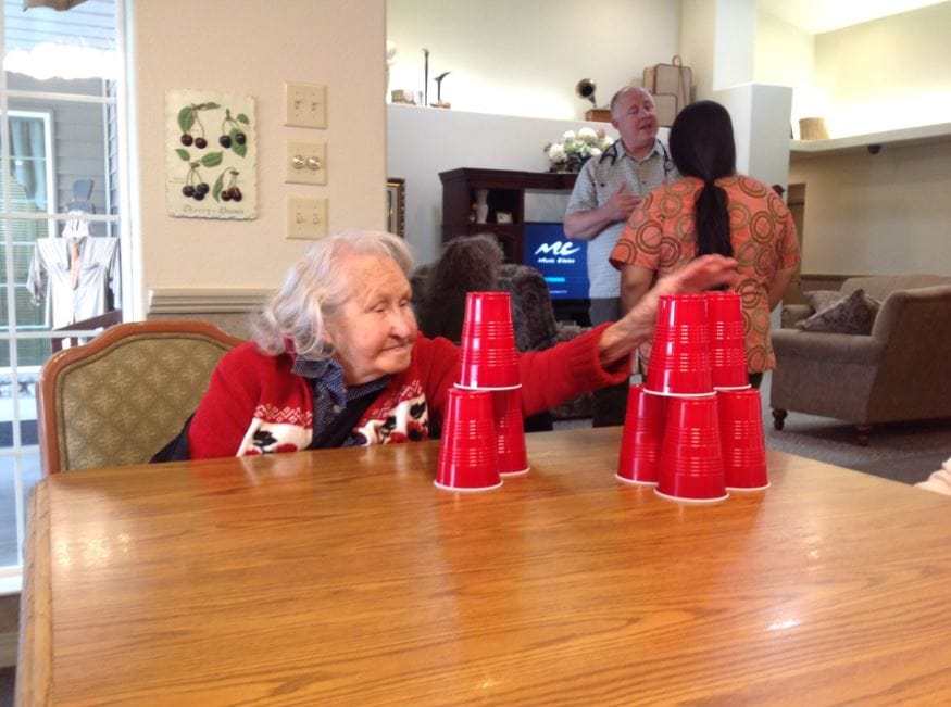 An elderly woman stacking red cups during a game.