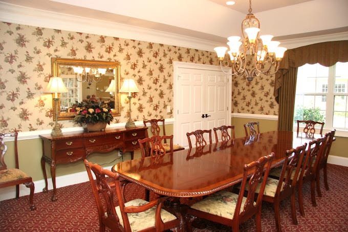 Elegant dining room with a long wooden table and floral wallpaper.