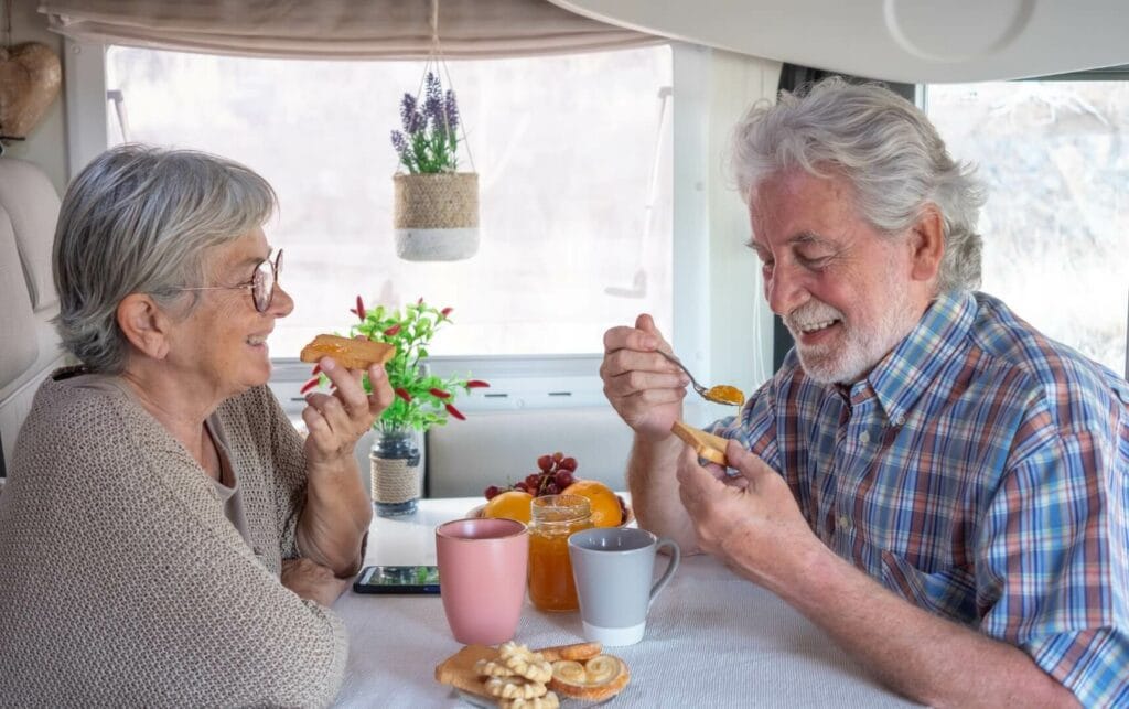 Two seniors enjoying snacks together indoors.
