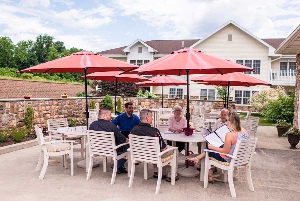 Residents and staff enjoying time outdoors at tables.