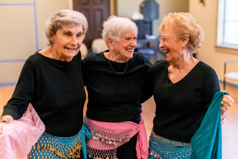 Three seniors smiling during a dance activity.