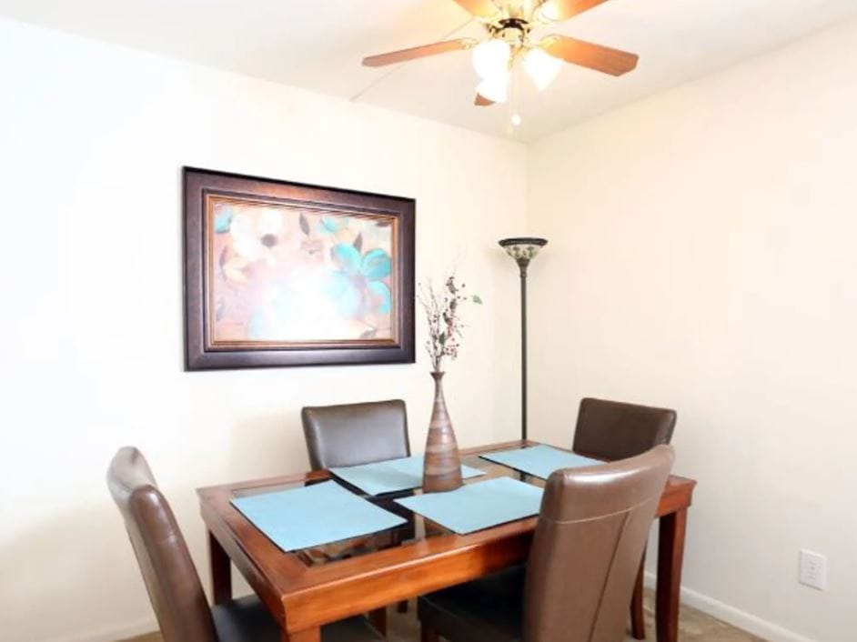 A dining table with four chairs and decorative items in a well-lit room.