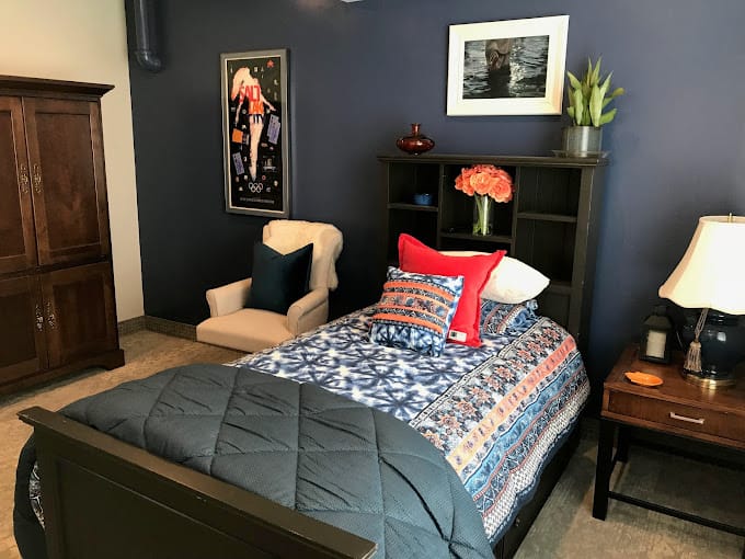 Well-decorated bedroom featuring a bed, armchair, and furnishings.