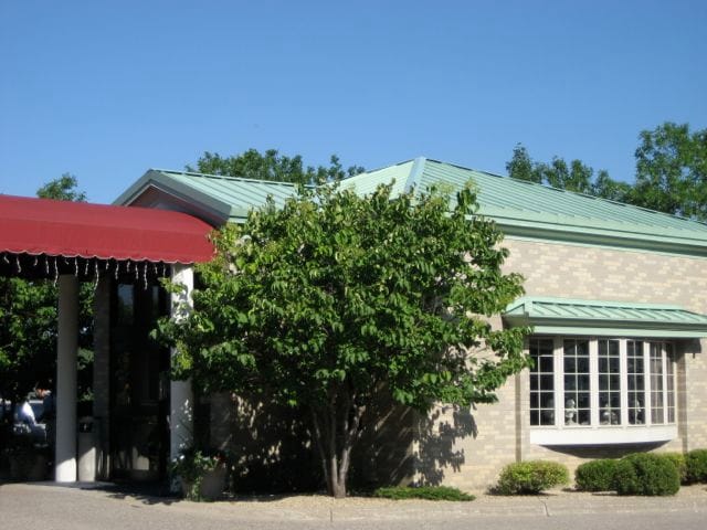 Building entrance with a green metal roof and a red awning.