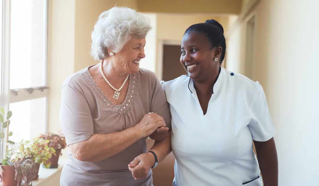 A resident and staff member laughing in a hallway