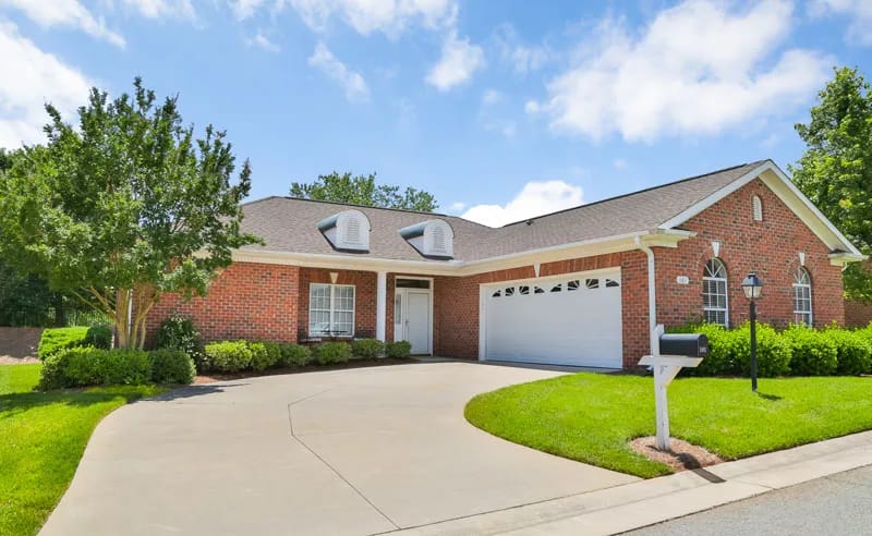 Exterior view of a red brick house with driveway and greenery