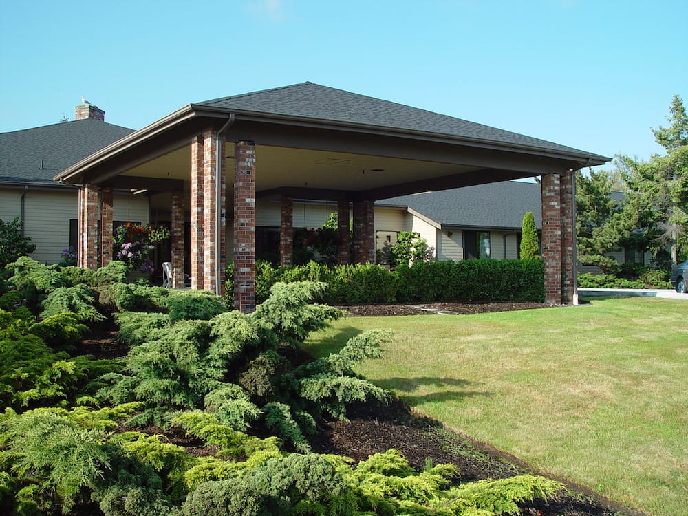 Covered outdoor area with landscaping in front of a senior living facility