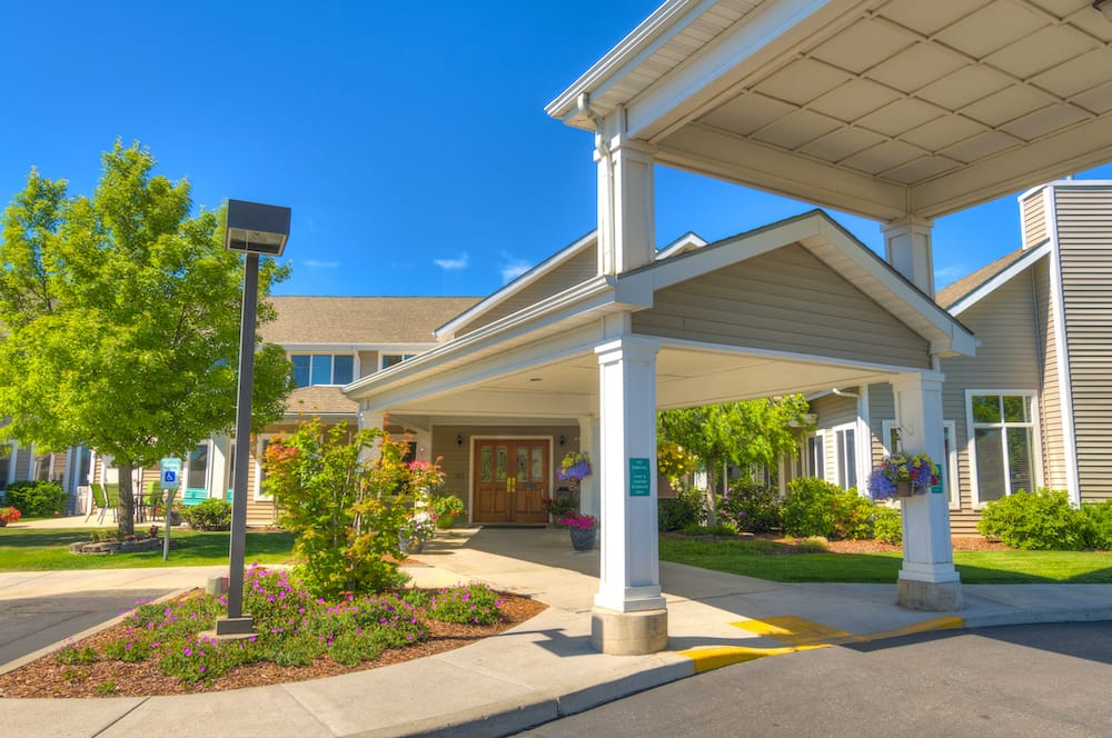Front entrance of a senior living facility with vibrant landscaping