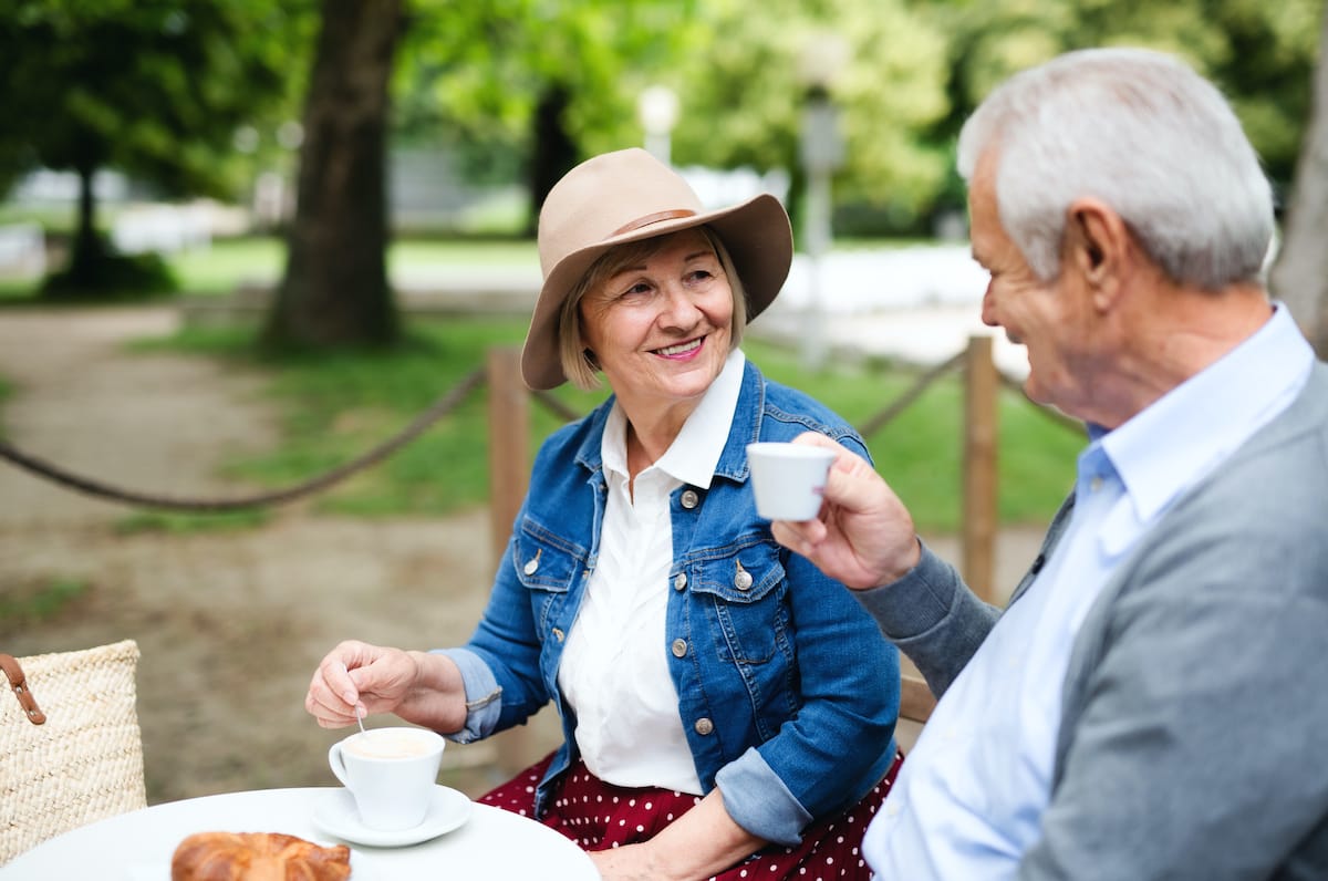 Two seniors enjoying coffee outdoors in a park
