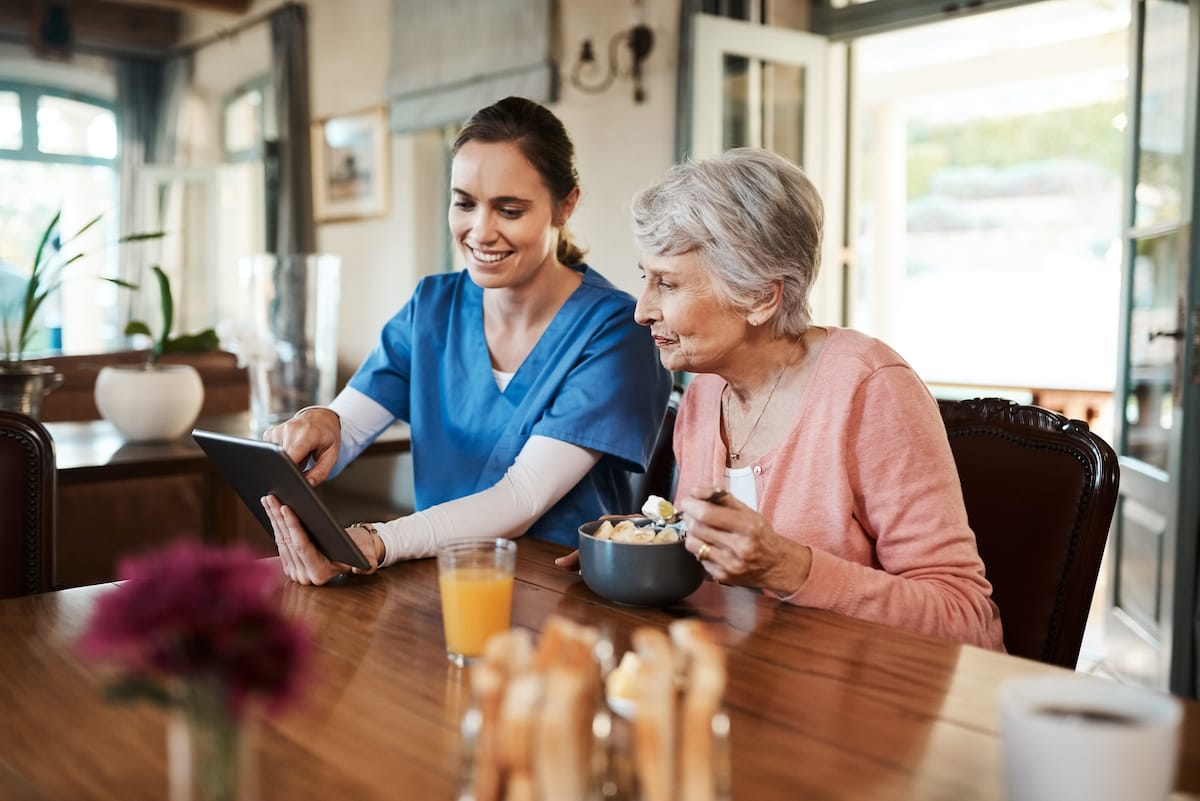A caregiver helping a resident with a tablet.