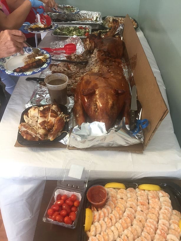 A vibrant spread of food including shrimp, rotisserie chicken, and a roasted pig.