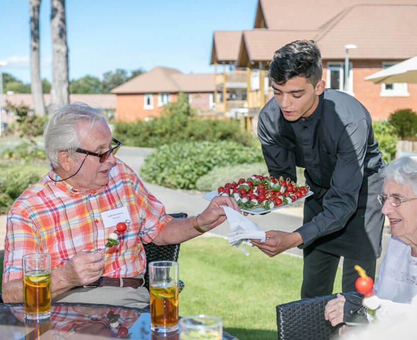 Residents enjoying food and drinks outside under a sunny sky