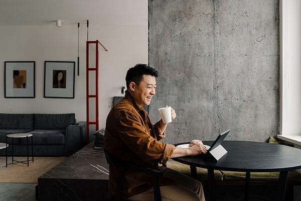 Man enjoying coffee while working on a tablet