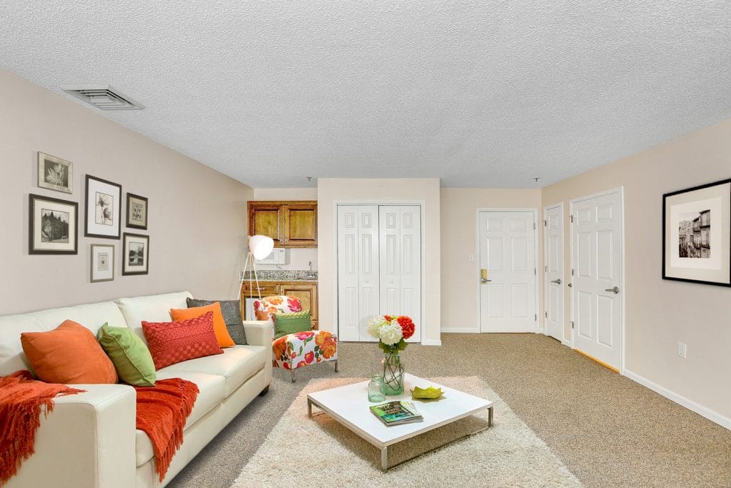 A bright living room with a white couch, colorful pillows, and a coffee table.