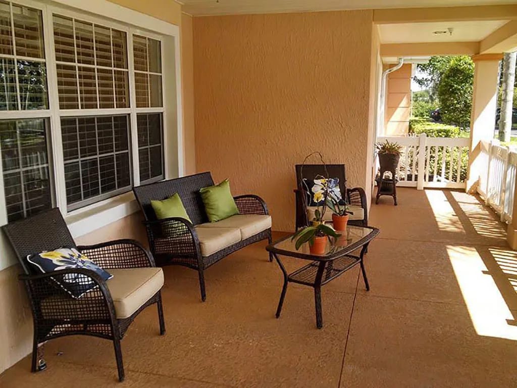 Comfortable seating area on a porch with potted plants.