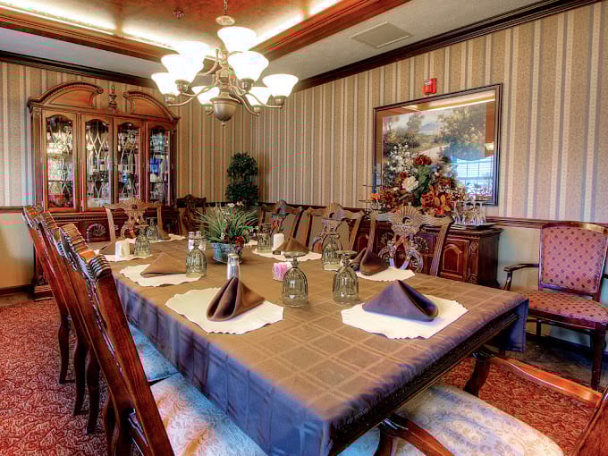 Dining room with a large table set for a meal, decorated with glassware and plants