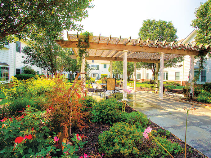 Lush garden with seating area and pergola at The Heritage at Shalimar Gardens