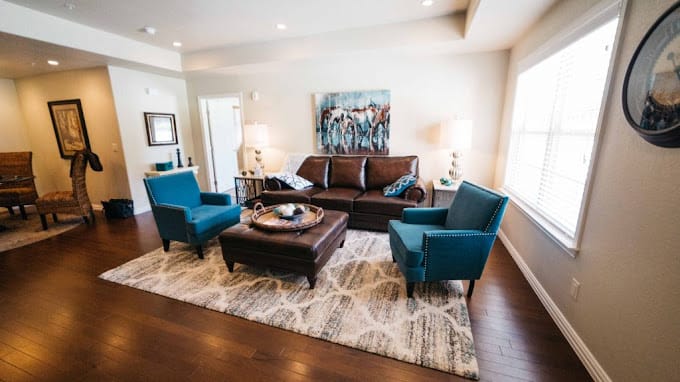 Living room with brown sofa, blue chairs, and art on the wall