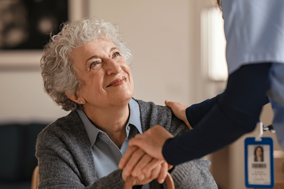 A caregiver and a senior woman share a warm moment.