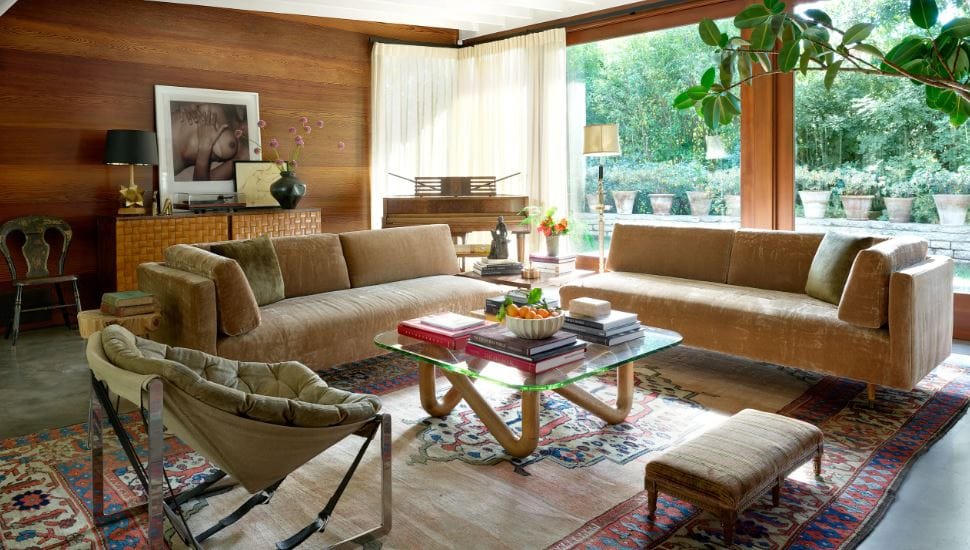 A cozy and stylish living room with sofas, a glass coffee table, and large windows.