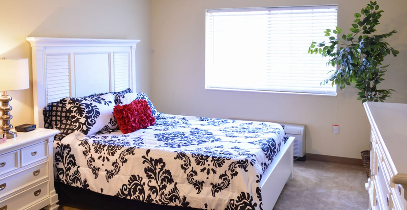 A well-appointed bedroom featuring a bed with a patterned quilt and bedside lamp.