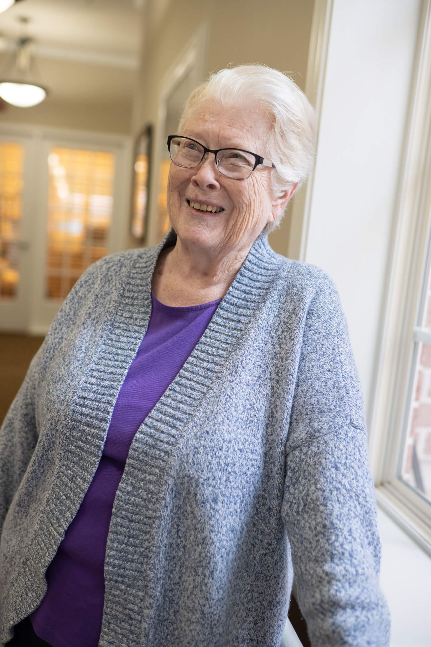 A smiling elderly woman in a cozy corridor