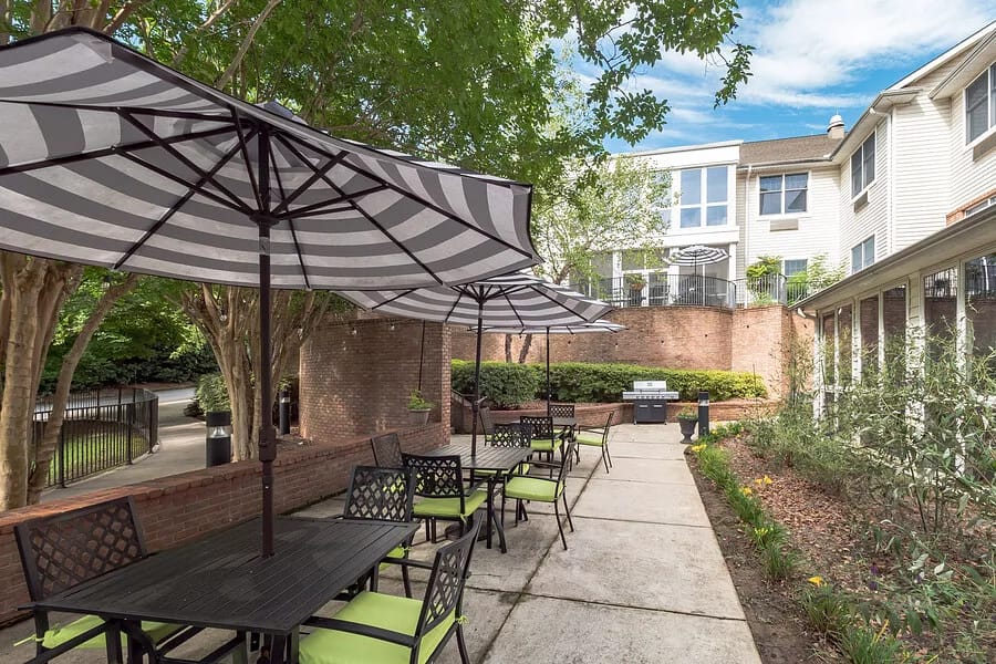 Outdoor patio with tables and umbrellas at The Parker senior living facility.