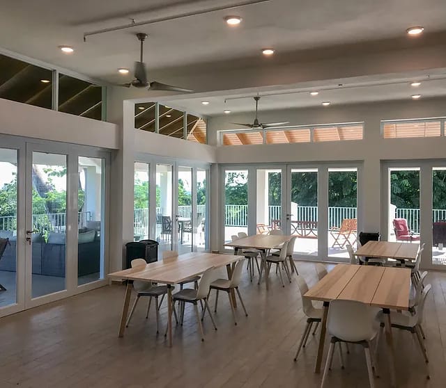 Spacious common area with dining tables and chairs, large windows