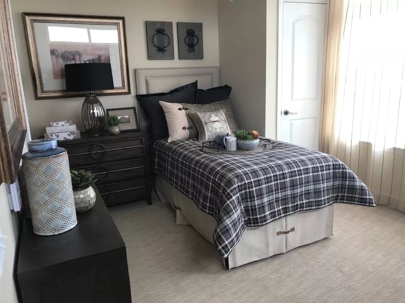 A well-decorated bedroom featuring a bed with plaid bedding, a lamp, and decorative items.