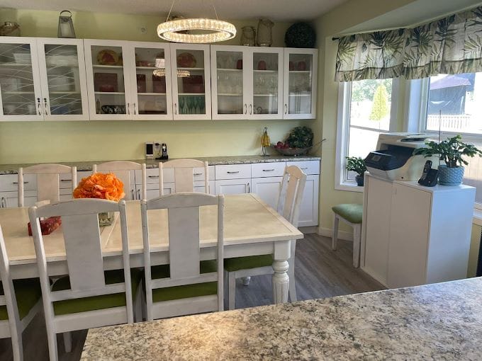 Bright kitchen and dining area with white furniture and green accents.