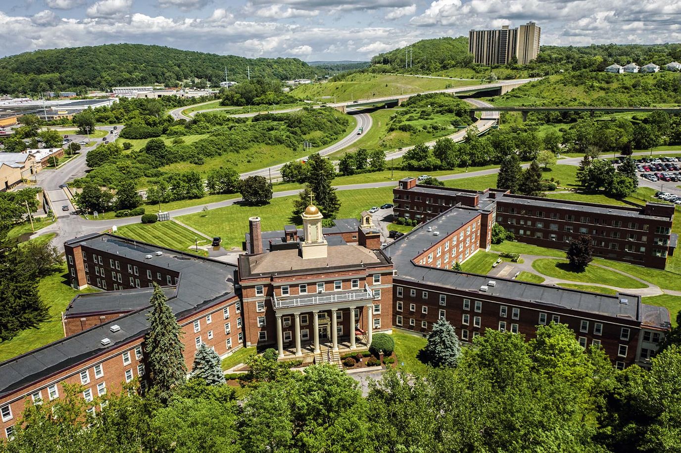 Aerial view of Loretto Community Residences with green landscape and highway in the background.