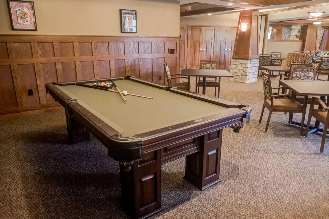 Billiards table with balls and cues in a senior living lounge