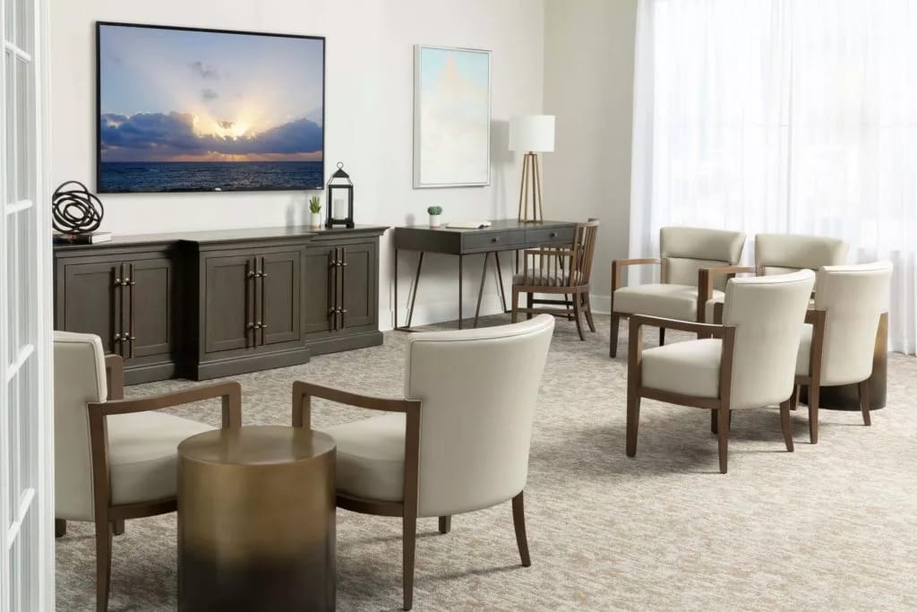 Spacious living room with white chairs, a coffee table, and a large TV