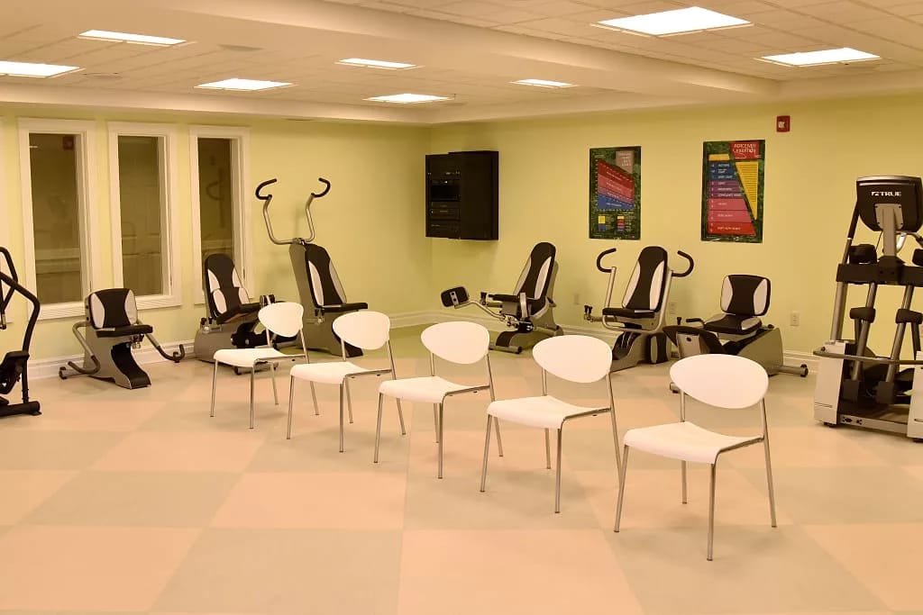 Fitness equipment and chairs in a brightly lit exercise room